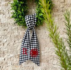 a black and white checkered bow hanging on a brick wall next to a wreath