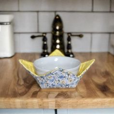 a white bowl sitting on top of a wooden counter next to a faucet