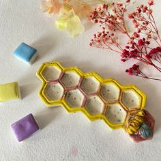 the honeycomb is made out of clay and sits next to some flower stems, wax cubes, and other crafting supplies