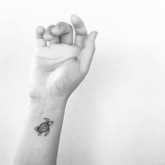 a small turtle tattoo on the left wrist and right hand is shown in black and white