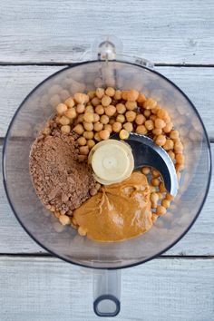 a food processor filled with peanut butter and chickpeas on top of a wooden table