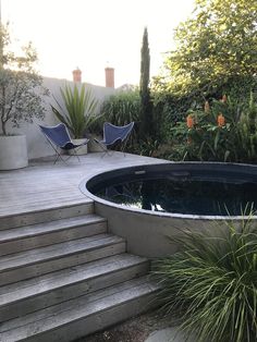 an outdoor swimming pool with steps leading up to it and two lawn chairs in the background