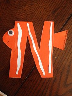 an orange fish made out of paper sitting on top of a wooden table