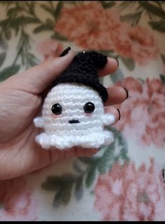 a small crocheted doll with a black hat on it's head is held in someone's hand