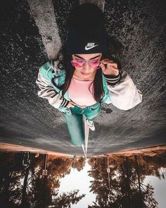 a girl wearing sunglasses and a hat is standing on a skateboard in the air