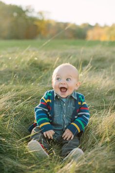 a baby is sitting in the grass with his mouth wide open and eyes wide open