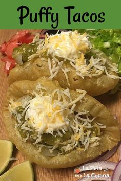 two pita breads with cheese and vegetables on a cutting board next to sliced limes