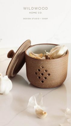 a bowl with some food inside of it on a white table next to garlic and flowers