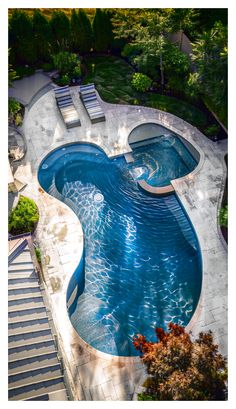 an aerial view of a swimming pool with steps leading up to it and trees in the background