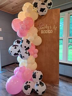 a bunch of balloons that are in the shape of cows and cow heads on a wooden floor