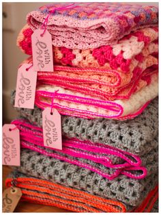 a stack of crocheted blankets with price tags on them