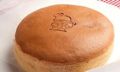 a round cake sitting on top of a white plate next to a red and white checkered table cloth