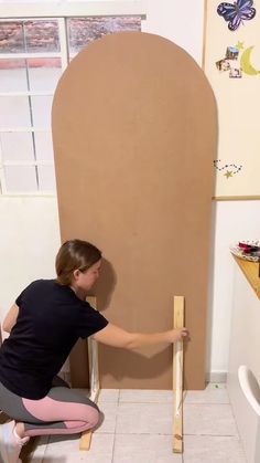 a woman kneeling on the floor with a piece of wood in front of her