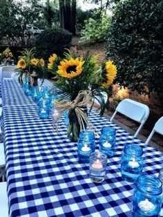 the table is set with sunflowers and blue glass vases for centerpieces