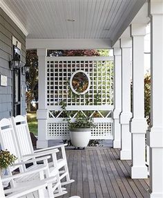 two white rocking chairs sitting on a porch