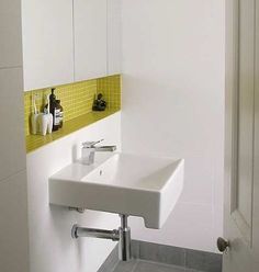 a white sink sitting under a bathroom mirror next to a wall mounted faucet