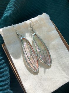 a pair of earrings sitting on top of a cloth