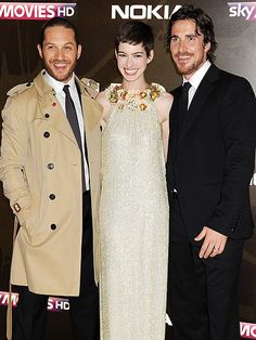 three people standing next to each other on a red carpet