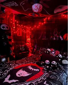 a bedroom decorated in black and red with skulls on the bedspread, lights strung from above