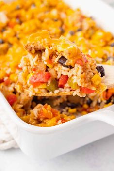 a spoon full of mexican rice casserole with black beans, peppers and corn