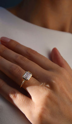 a woman's hand with a diamond ring on top of her left hand,