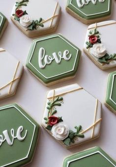 decorated cookies with the words love and roses are arranged on a white tablecloth that says love