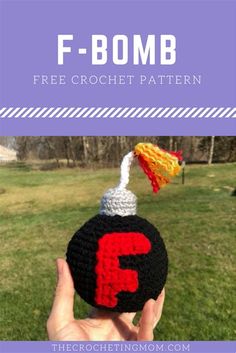 a hand holding up a crocheted hat with the letter f on it