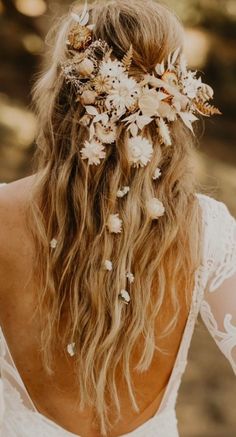 the back of a woman's head with flowers in her hair, wearing a white dress