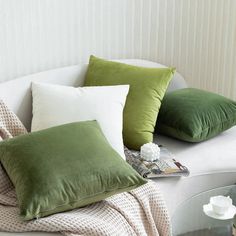 green and white pillows sitting on top of a couch