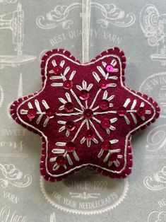 a red ornament hanging from a string on top of a gray tablecloth