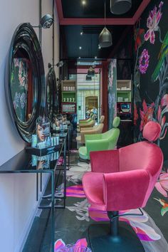 the interior of a hair salon with colorful chairs and artwork on the wall behind it