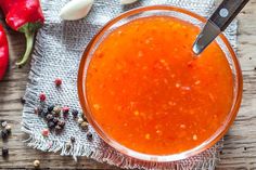 a glass bowl filled with sauce next to red peppers and garlic