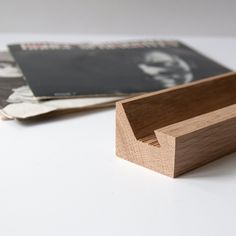 a wooden box sitting on top of a white table next to a magazine holder with a black and white photo