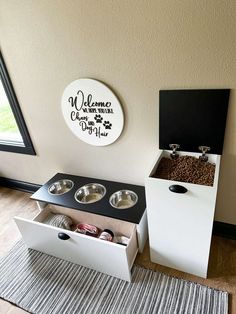 a dog house with two bowls in it and a sign on the wall