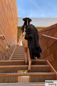 a woman in a graduation gown walking down some stairs