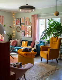 a living room filled with furniture and lots of plants on the wall next to a window