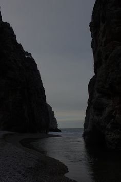 two large rocks sticking out of the water next to each other near an ocean shore