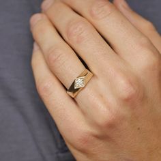 a close up of a person's hand wearing a gold ring with a diamond