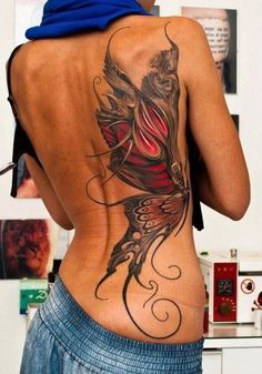 the back of a woman's body with tattoos on her lower and upper back