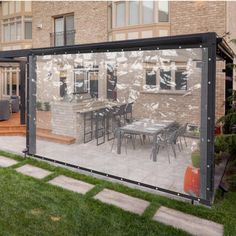 a large glass enclosed patio area in front of a brick building with an outdoor dining table and chairs