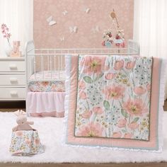 a baby crib bedding set with pink flowers and butterflies on the wall next to it