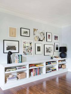 a living room with pictures on the wall and bookshelves in front of it