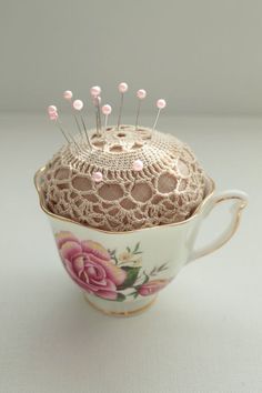 a cup with some pins in it sitting on top of a table