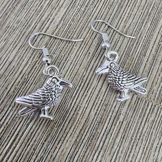 Crow charms hang from silver colored ear wire. The bird earrings are almost 1.5 inch long. Silver Dangle Jewelry With Bird Design, Silver Bird-shaped Earrings For Pierced Ears, Silver Bird Design Drop Earrings, Silver Drop Earrings With Bird Design, Bird Earrings, Etsy Earrings Dangle, Ear Wire, Earrings Silver, Silver Color