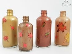 four glass bottles with autumn leaves painted on them