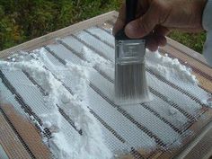 a person holding a paint brush over some white powder