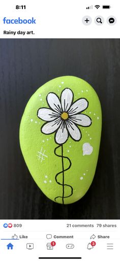 a green rock with a white flower painted on it