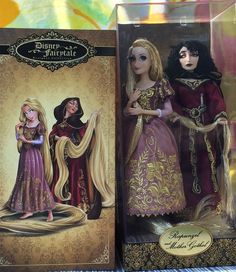 two dolls are shown next to each other in their packagings, one is wearing a purple dress and the other has a gold trim