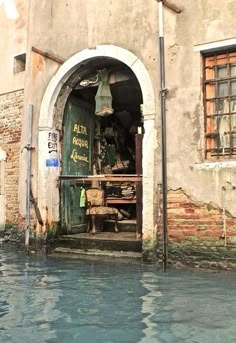 a boat is in the water next to a building with an open door on it