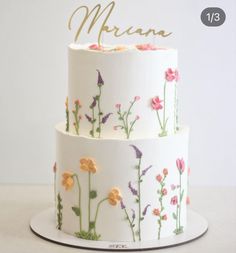 a three tiered cake decorated with flowers and the word merana on it's side